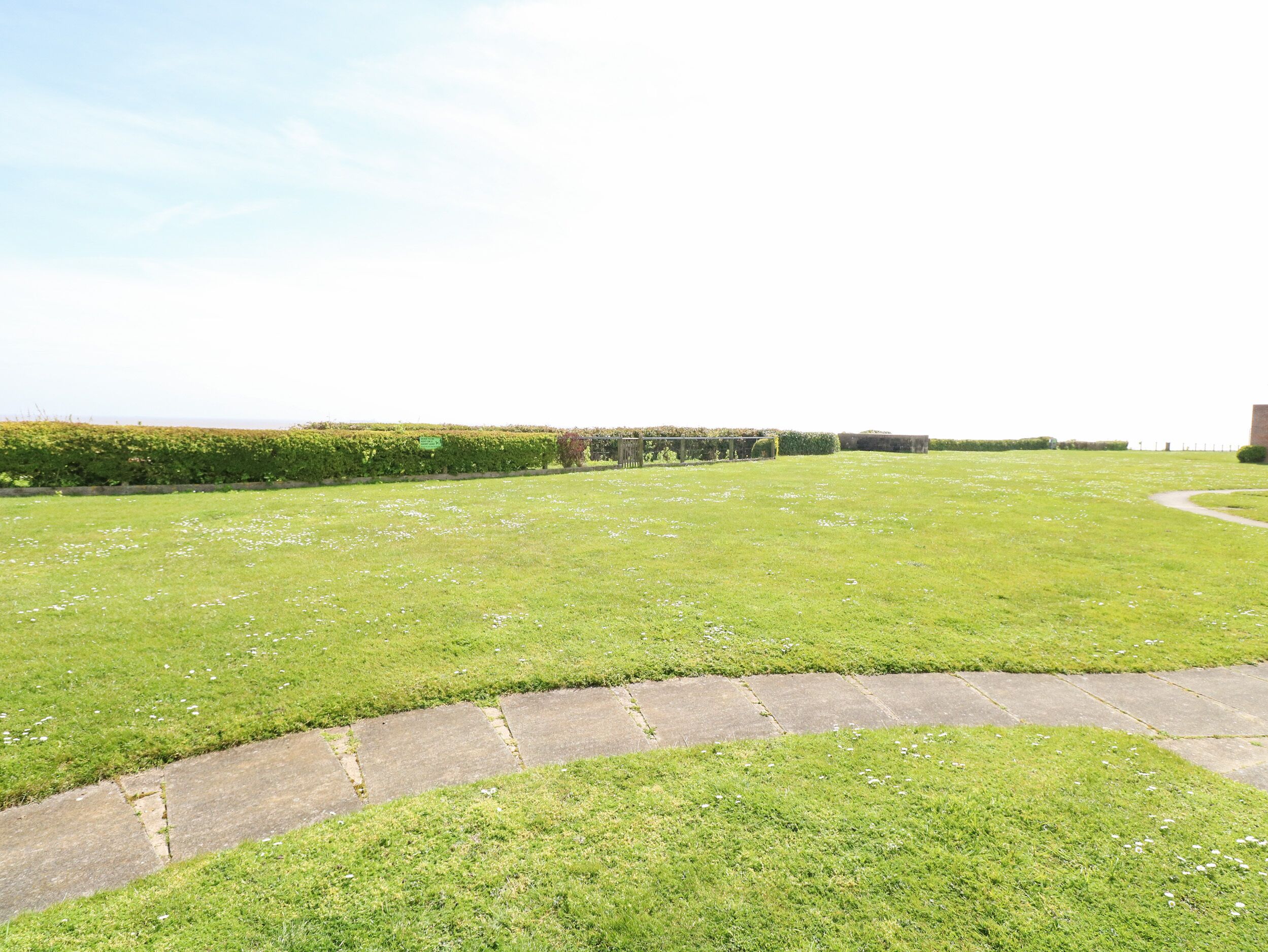 A grassy area with a stone pathway leading to a building.