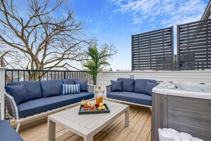 Une terrasse extérieure avec un canapé, une table basse avec des boissons et un jacuzzi.