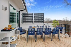 Une terrasse avec une table et des chaises, un petit chariot de service et une plante en pot.