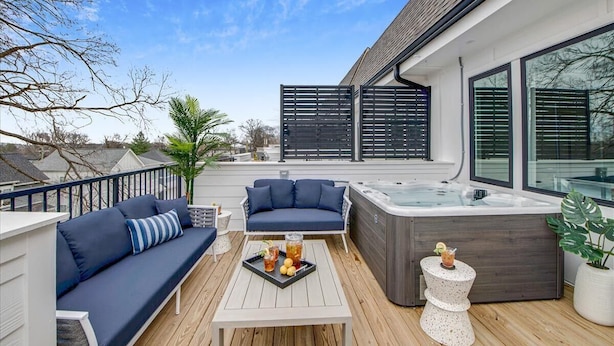 Una terrazza con divano, vasca idromassaggio e tavolino con bevande.