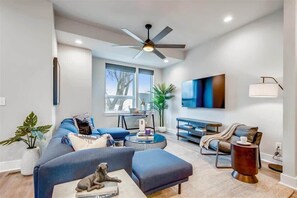Relax in this stylish living room with a large sofa, coffee table, and TV mounted on the wall.