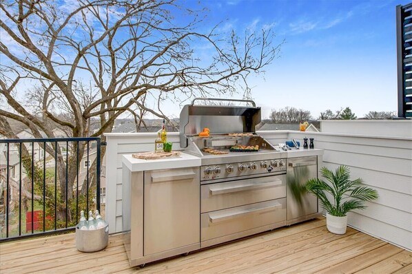 An outdoor kitchen with a grill, a sink, and a countertop.