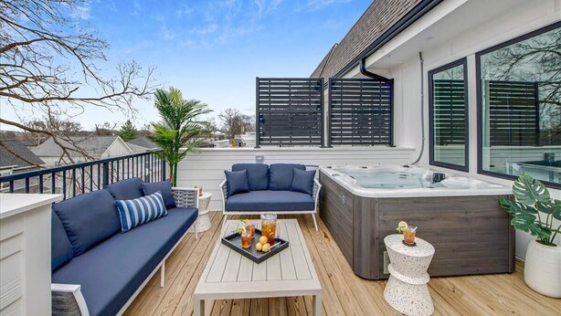 Una terraza con un sofá, un jacuzzi y una mesa con bebidas.