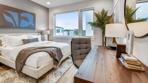 Een moderne slaapkamer met een bed, een stoel, een bureau, een groot raam en een plafondventilator.