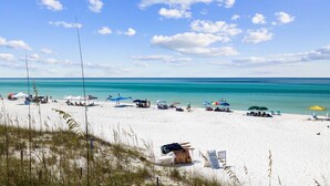 A beach with white sand, clear turquoise water, and a few umbrellas and beach chairs. - Gulf Views | Pool | Close to Beach | Elevator (Santa Rosa Beach)