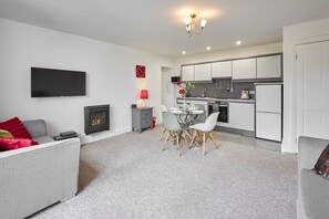 Relax in this stylish living room with a sofa, flat-screen TV, and dining area.