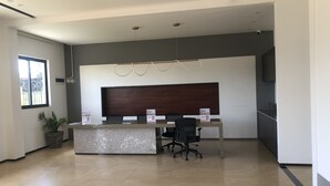 A modern reception area with a marble counter, black office chairs, and a dark wood panel above the counter. - Phoenix Villa (Kigali)