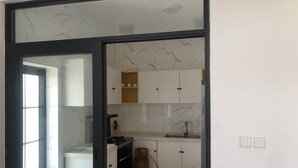 A compact kitchen with white cabinets, a gas stove, and a sink. - Phoenix Villa (Kigali)