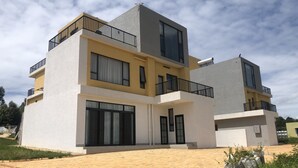 A modern two-story residential building with balconies, large windows, and a paved driveway. - Phoenix Villa (Kigali)