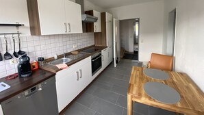 Una cocina moderna con armarios blancos, un horno empotrado y una mesa de madera con dos sillas.
