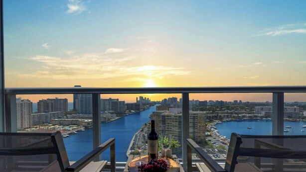 En balkon med udsigt over byen, en flaske vin og et fad med frugt.