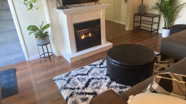 A living room with a fireplace, a ceiling fan, and a television.