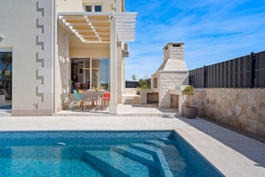 Uma casa moderna com piscina, área de estar externa e lareira de pedra.