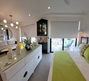 A modern bedroom with a bed, bedside table, and a view of the outside.