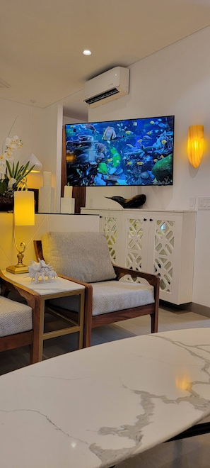 A modern living room with a flat-screen TV, comfortable seating, a coffee table, and decorative elements like a lamp and an aquarium. - Blissful Ocean-View Penthouse with Rooftop Pool (Puerto Vallarta)
