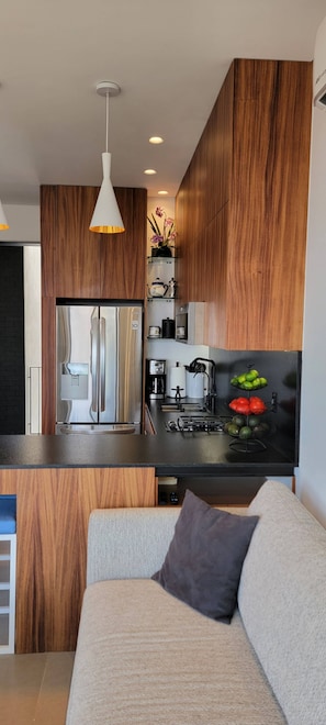 A modern kitchen with wooden cabinets, a stainless steel refrigerator, and a built-in oven.