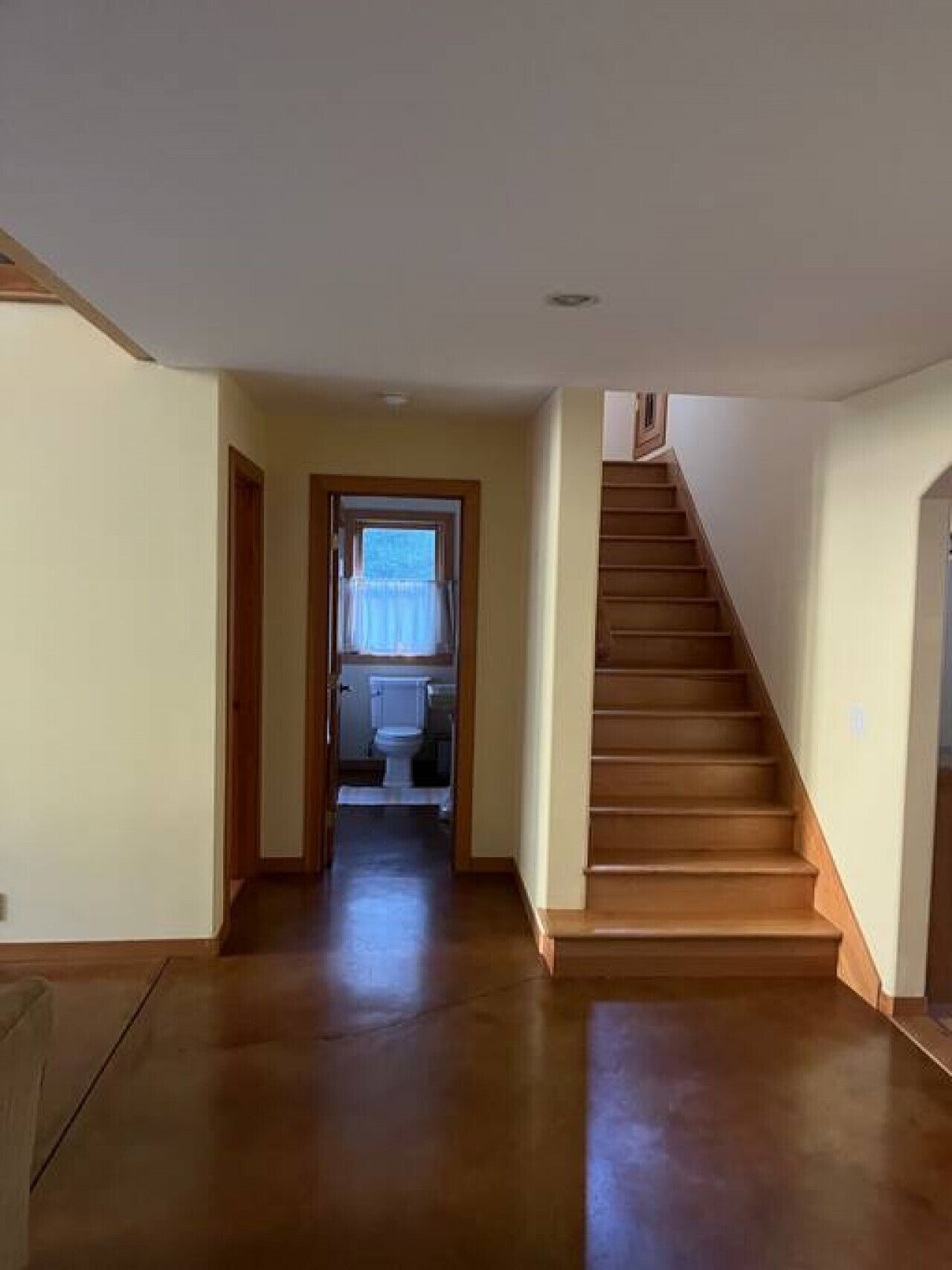 Un couloir avec un escalier en bois menant à un deuxième étage.