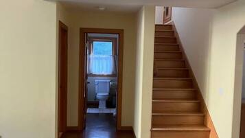 Un couloir avec un escalier en bois menant à un deuxième étage.