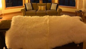 A room with a large window, a sofa, and a fur throw. - Redwood Creek Getaway! (Redway)