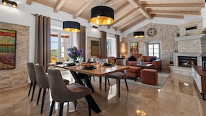 Cozy living area with a high ceiling, dining table, and comfortable seating area featuring a fireplace.