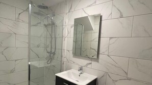 Une salle de bain moderne avec une douche à parois de verre, un meuble-lavabo noir et des toilettes.