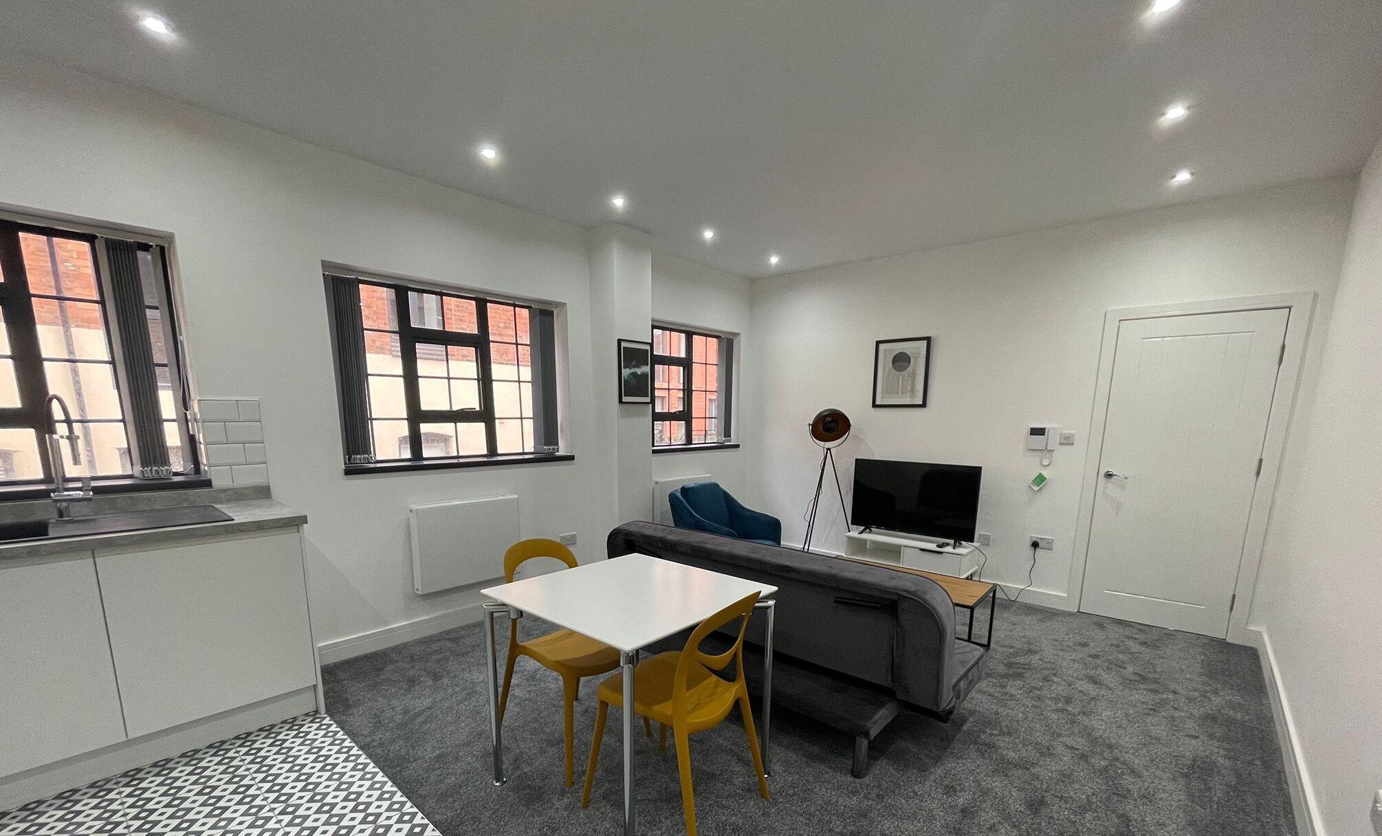 A compact living space with a kitchenette, a sofa, a dining table with chairs, and a television.
