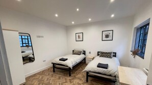 Une chambre avec deux lits, un miroir et une fenêtre.