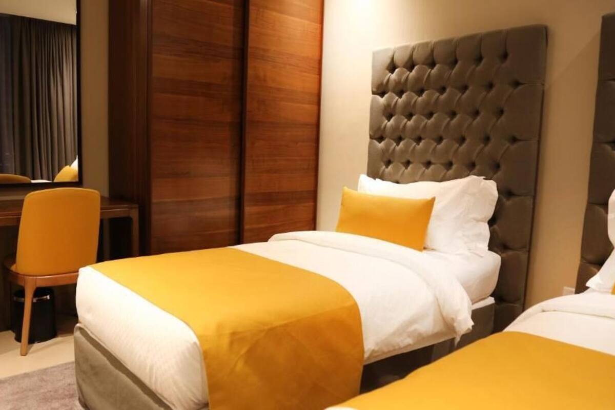 A hotel room with two beds, a desk, and a chair.