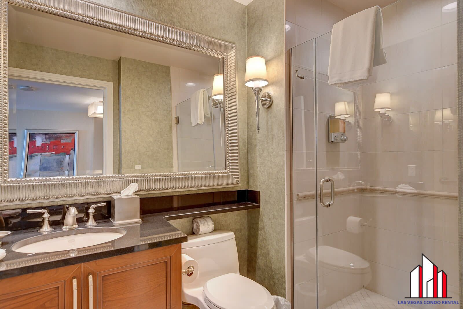Een moderne badkamer met twee wastafels, een grote spiegel, een douchecabine met glazen wanden en een toilet.