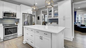 A modern kitchen with white cabinetry, stainless steel appliances, and a large island. - Award-Winning Resort Amenities | Grand Pavilion 71 by Wild Dunes (Isle of Palms)