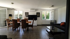 A modern living room with a dining area, a flat-screen TV, and a sofa. - La Villa de Jade (Orange)