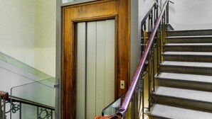 A staircase with a wooden door at the bottom, metal railings, and a glass elevator shaft. - Conte Jacopo - La Dimora degli Affreschi Florence (Florence)