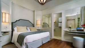 Une chambre à coucher bien rangée, avec un lit, des lampes de chevet, un miroir et un petit tabouret.
