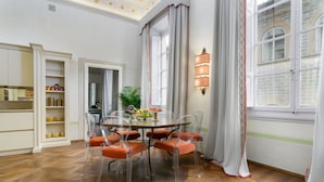 Un coin repas avec une table ronde, six chaises et une plante en pot.