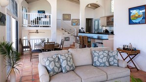 A spacious living area with a sofa, a dining table, and a kitchen in the background. - Sea Turtle Villa: Stunning Views! Newly Refurnished! (St John)