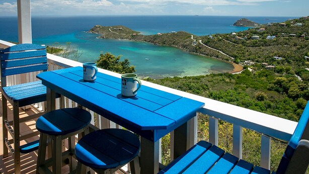 A balcony with blue furniture overlooking a coastal view. - Sea Turtle Villa: Stunning Views! Newly Refurnished! (St John)