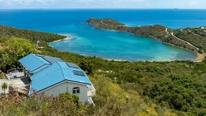 A coastal property with a house featuring a blue roof, surrounded by lush greenery and a clear view of the turquoise sea and distant island. - Sea Turtle Villa: Stunning Views! Newly Refurnished! (St John)