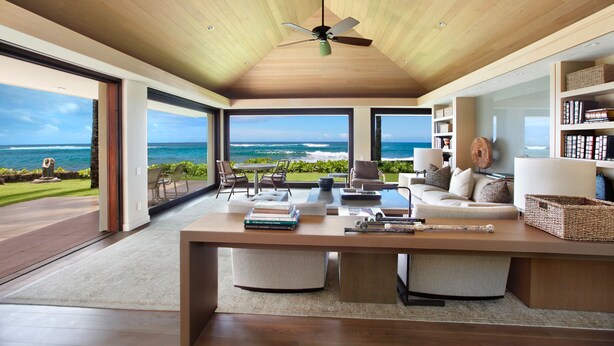 Un amplio salón con una gran mesa de madera, asientos cómodos y vista al océano.