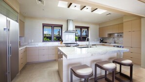 Una cocina moderna con una isla grande, electrodomésticos de acero inoxidable y vistas al exterior.
