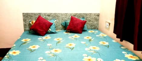 A bed with a floral bedspread and two red pillows.