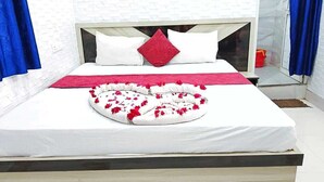 A neatly made bed with a heart-shaped arrangement of red flowers and white pillows. - Swastik Hotel  (Deoghar)