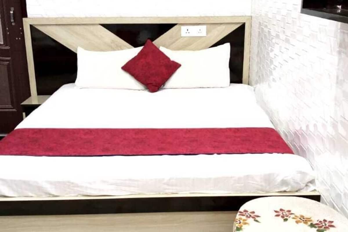 A bed with a wooden headboard, white bedding, and a red throw blanket.