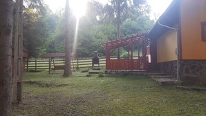 A rustic outdoor area with a wooden pergola, a stone wall, and a brick oven. - Private vacation home in the middle of the Harghita mountains surrounded by (Vărșag)