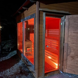 A wooden cabin with a glass door, a visible fireplace, and a metal door frame.