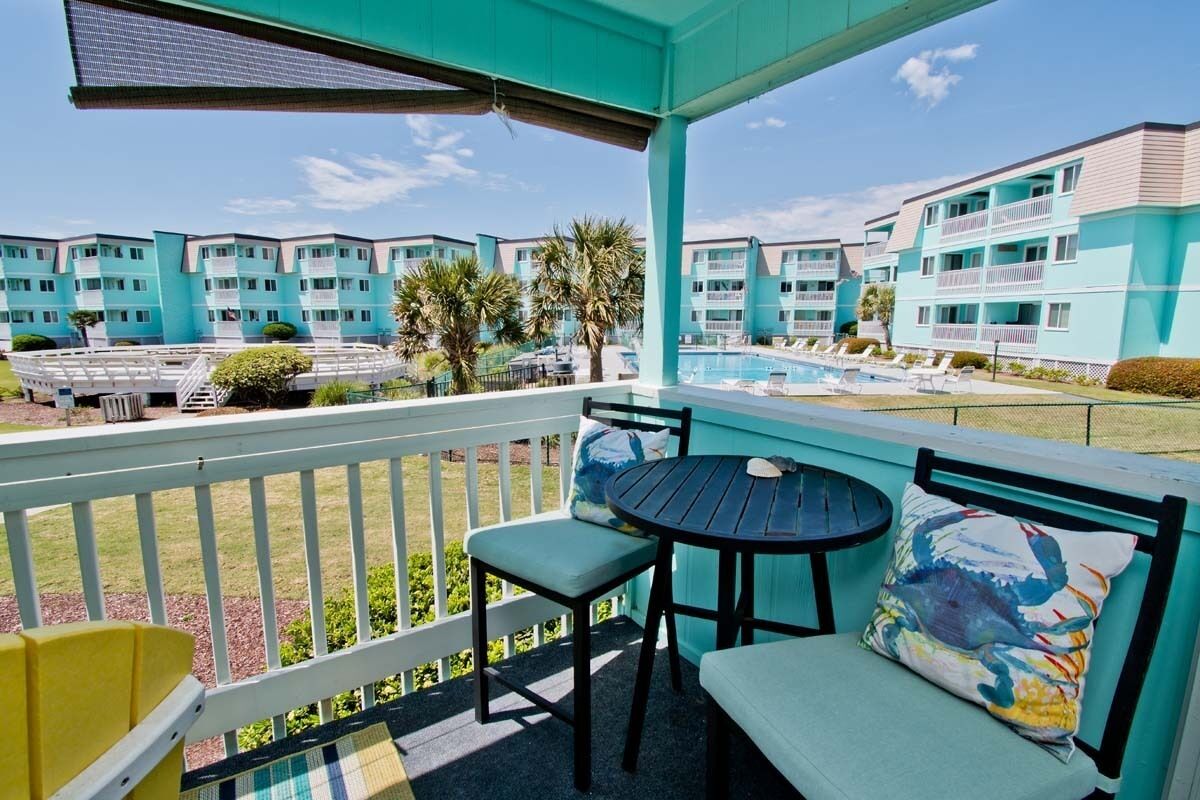 Un balcon donnant sur une piscine, avec une table et des chaises.