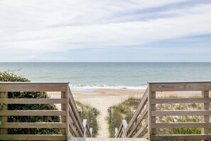 A wooden staircase leading to a beach with a view of the ocean.
