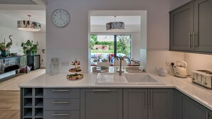 A modern kitchen with a large island, grey cabinets, a white countertop, and a view to the outdoors. - Fox and Hare (Shrawardine)