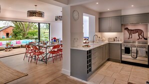 A modern kitchen with grey cabinets, a built-in oven, and a large island with a sink. - Fox and Hare (Shrawardine)