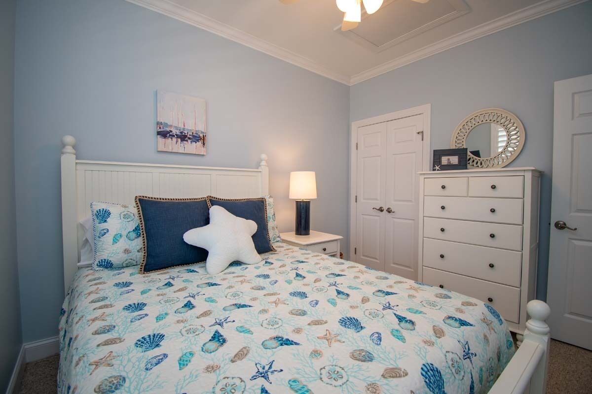 A bedroom with a bed, a nightstand, a dresser, and a door.