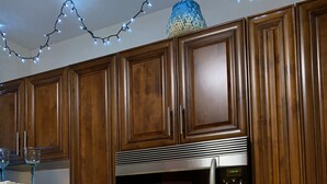 A kitchen with wooden cabinets, a microwave, a stove, and various kitchen utensils. - Beach Side Hideaway 1 Bedroom Condo by RedAwning (Norfolk)